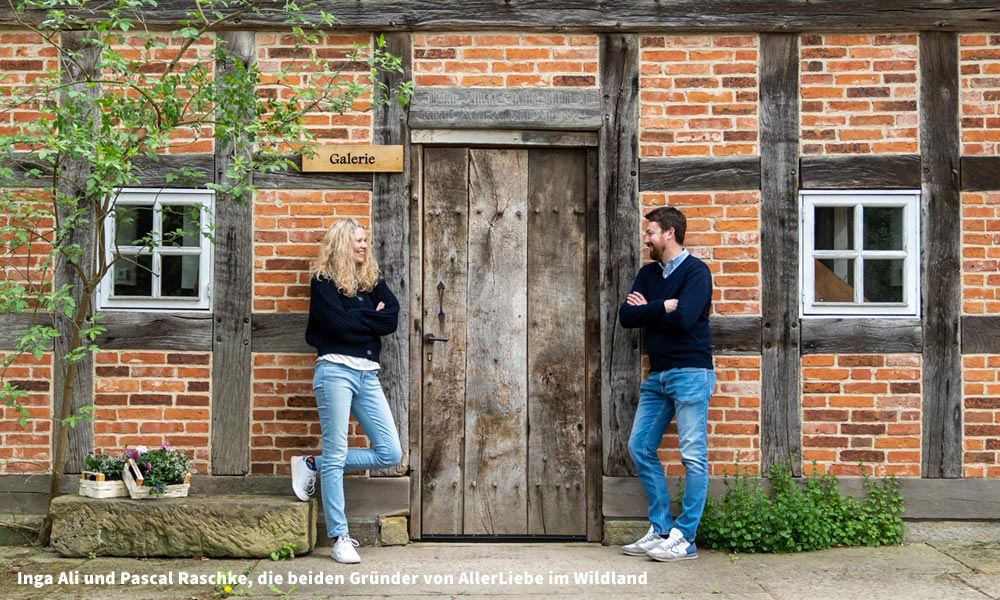 Inga Ali und Pascal Raschke, die beiden Gründer von der Lovebrand AllerLiebe schauen sich links und rechts neben der Tür eines Fachwerkhauses an.